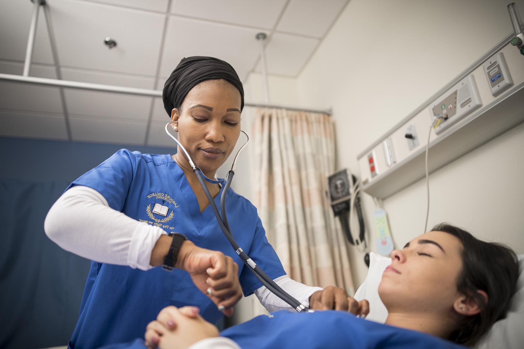 Student nurse with stethoscope taking vitals